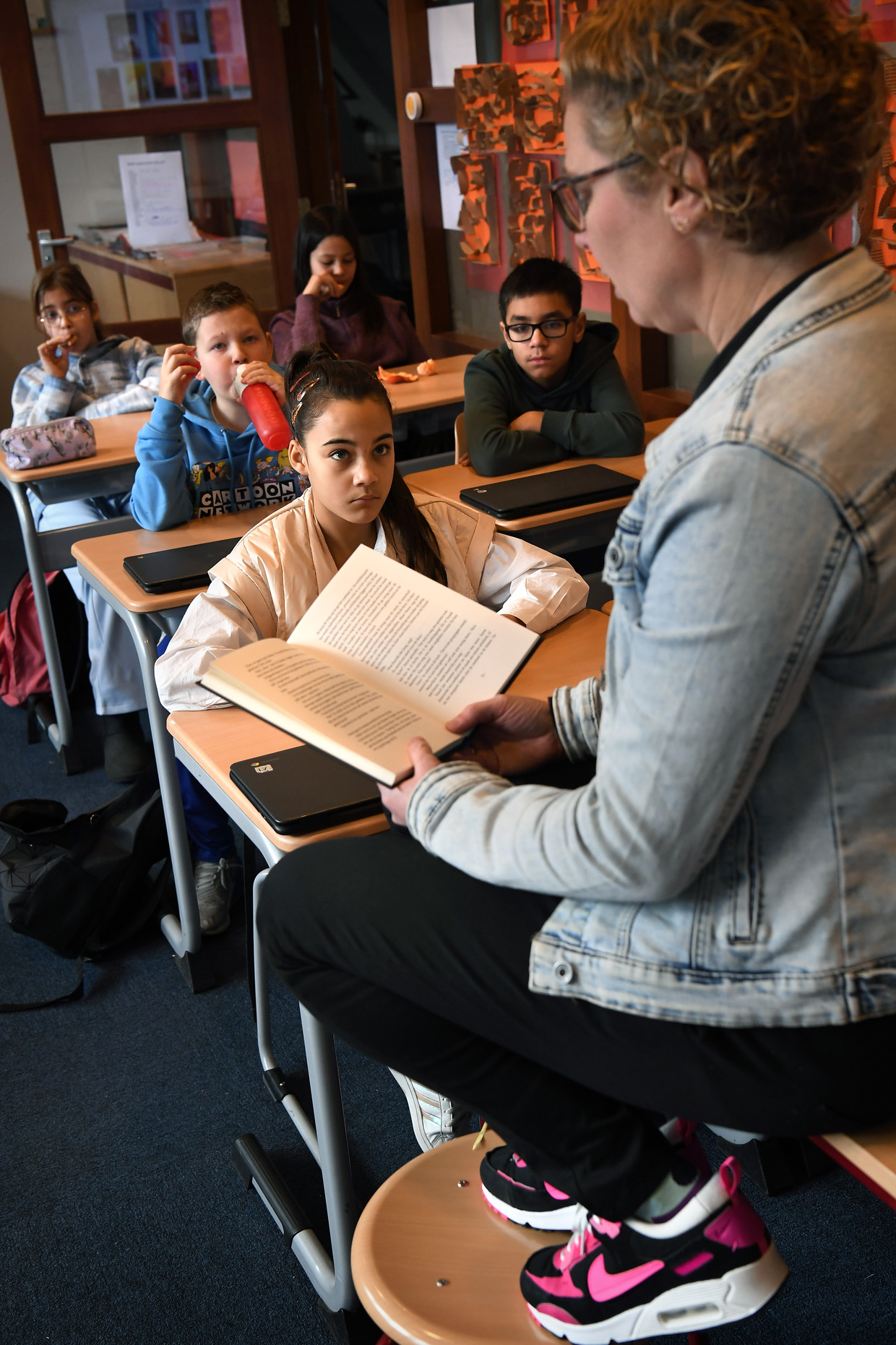 Een docent van Kindcentrum Emma in Rotterdam leest leerlingen uit groep 8 voor. Beeld Marcel van den Bergh / de Volkskrant